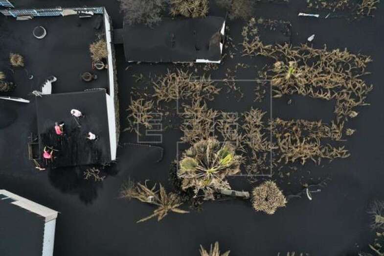 Imagen de archivo de un grupo de personas que limpian la ceniza volcánica del tejado de una de las viviendas de la localidad de Las Manchas que se encuentra totalmente deshabitada por la erupción del volcán de Cumbre Vieja / EFE Jesús Diges